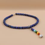 Handmade in Nepal by skilled artisans, this Seven Chakra Lapis Lazuli Stone Necklace enhances wisdom and communication, supporting your spiritual journey and promoting inner peace.