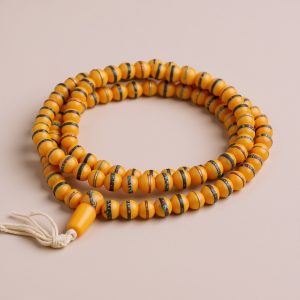 Yellow Resin Ambar Prayer Mala, handmade in Nepal by skilled artisans, serves as a powerful tool for meditation, fostering emotional balance and spiritual growth through its 108 beads.