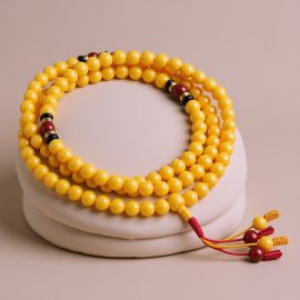 Handmade in Nepal by skilled artisans, this mala features yellow resin amber and carnelian spacers, promoting healing, creativity, and emotional balance on your spiritual path.