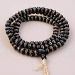 The Black Inlaid Yak Bone Prayer Mala, handmade in Nepal by skilled artisans, embodies the essence of impermanence, guiding practitioners in compassion and healing through mantra meditation.