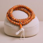 Handmade in Nepal by skilled artisans, this orange inlaid yak bone prayer mala symbolizes peace, wisdom, and strength, guiding your meditation and spiritual journey.