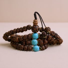 This handmade Rudraksh seed mala from Nepal, featuring turquoise spacers, embodies Lord Shiva's essence, promoting spiritual connection and protection through its sacred vibrations.