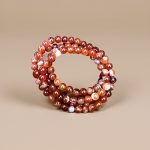 This handmade mala from Nepal features 108 natural fire agate beads, promoting protection and purification, and supporting mantra recitation for spiritual practice and personal growth.