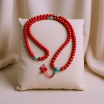 This japa mala, crafted from vibrant red coral and blue turquoise, is handmade in Nepal by skilled artisans, serving as a sacred tool for meditation and spiritual practice.