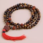Tiger Eye Stone Prayer Mala, handmade in Nepal by skilled artisans, serves as a powerful companion in meditation, promoting grounding, protection, and inner peace on your spiritual journey.