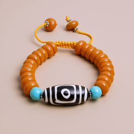 The Dzi Bead Resin Ambar Wrist Mala is a handmade treasure from Nepal, crafted by skilled artisans, embodying healing energies and spiritual protection for your journey.