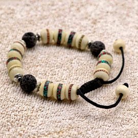 This handmade wrist mala, crafted by skilled artisans in Nepal, features yak bone and lava rock, symbolizing impermanence and grounding, guiding us toward meditation and inner peace.