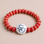 Handmade in Nepal by skilled artisans, this wrist mala features red inlaid yak bone and a Hindu Om symbol, serving as a reminder of mindfulness and spiritual grounding.