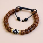 Handmade in Nepal by skilled artisans, this wrist mala features sacred Rudraksha seeds and an Amulating Dzi bead, fostering spiritual growth, protection, and divine connection.