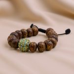 Handmade in Nepal by skilled artisans, this Antique Flat Bodhi Seed Wrist Mala features blue and golden inlaid beads, aiding mindfulness and symbolizing the path to enlightenment.