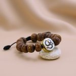 Handmade in Nepal by skilled artisans, this Antique Flat Bodhi Seed Wrist Mala features a sacred Hindu Om on conch shell, embodying wisdom and aiding in meditation.