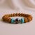 This handmade wrist mala, crafted in Nepal by skilled artisans, features five-faced Rudraksha beads and Hematite, serving as a spiritual tool for grounding and divine connection.
