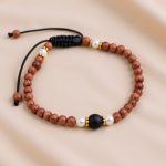Handmade in Nepal by skilled artisans, this 4 mm wrist mala of shining stone and matte onyx symbolizes light and stability, guiding you on your spiritual journey.