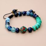 Handmade in Nepal by skilled artisans, this wrist mala features inlaid brass and blue agate stones, promoting tranquility and supporting your spiritual practice. Embrace its calming energy.