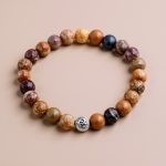Handmade in Nepal by skilled artisans, this Jasper stone wrist mala features a sacred Om spacer, symbolizing the connection between earth and spirit, and enhancing your meditation practice.