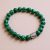 This handmade wrist mala from Nepal features malachite stones, promoting emotional balance and healing, with a Buddha head spacer symbolizing enlightenment and compassion. A sacred tool for meditation.