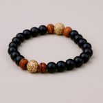 Handmade in Nepal by skilled artisans, this wrist mala features Matte Onyx and sacred Raktu and Lotus seeds, promoting emotional stability, spiritual growth, and resilience on your journey.