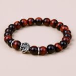 Handmade in Nepal by skilled artisans, this wrist mala features 22 Red Tiger Eye beads, promoting vitality and confidence, adorned with the sacred mantra &ldquo;Om Mani Padme Hum&rdquo; for spiritual clarity.
