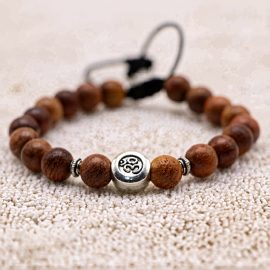 This handmade wrist mala, crafted by skilled artisans in Nepal, features Bayong wood and a sacred Om charm, fostering tranquility and spiritual connection for the wearer.