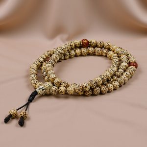 Handmade in Nepal, this 8mm Light Brown Lotus Seed Mala features a Tibetan Om carved carnelian spacer, symbolizing purity and resilience, supporting your meditation and spiritual journey.