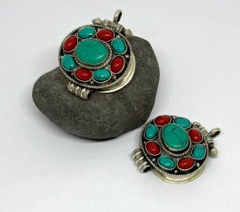 The gau, a sacred prayer box pendant, is handmade in Nepal by skilled artisans, serving as a portable shrine that connects the wearer to their spiritual journey.