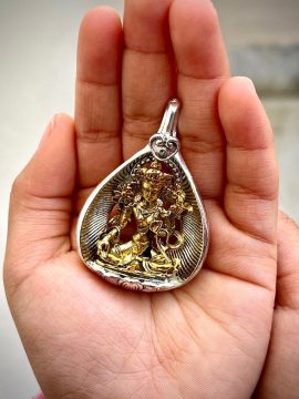 This handmade Nepalese pendant features Green Tara, embodying compassion and wisdom. Wear it as a sacred reminder of her protective energy on your spiritual journey.