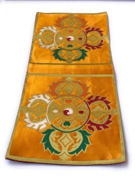 This handmade yellow double dorje placemat, crafted from traditional Tibetan silk brocade by skilled artisans in Nepal, enhances your sacred space for meditation and prayer.