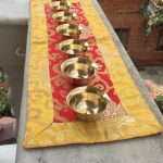 This set of seven handmade brass water offering bowls from Nepal fosters generosity and devotion, enhancing your spiritual practice through daily offerings on your shrine.