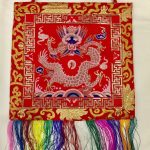 This handmade Tibetan wall hanging features a vibrant red protector dragon, symbolizing strength and protection. Crafted by skilled artisans in Nepal, it enriches your spiritual space.