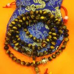 This handmade Tibetan Tiger Eye Stone Mala from Nepal features 108 beads, including mantra spacers and a prayer wheel, serving as a supportive companion in meditation and daily life.