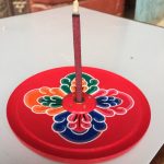 This handmade wooden incense burner from Nepal features intricate flower designs, serving as a sacred tool to enhance meditation and purify your space with fragrant smoke.