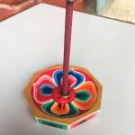 This handmade wooden incense burner from Nepal features a hand-painted lotus design, creating a sacred space for your incense offerings and elevating your spiritual practice.