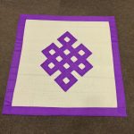 This handmade Tibetan table cover, crafted from pure cotton by skilled artisans in Nepal, features a timeless endless knot design, symbolizing the sacred interconnectedness of all life.