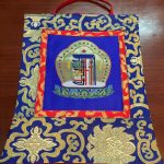 This handmade Tibetan Silk Brocade Blue Kalachakra wall hanging, crafted by skilled artisans in Nepal, invites mindfulness and embodies the teachings of time and cycles.