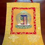 This handmade silk brocade Kalachakra wall hanging from Nepal embodies the sacred cycle of time, inviting peace and mindfulness into your space through its delicate lotus design.