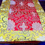This handmade red silk brocade table runner from Nepal features the sacred lotus design, symbolizing purity and enlightenment, perfect for enhancing your meditation space or altar.