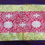 This handmade silk brocade table runner, crafted by skilled artisans in Nepal, beautifully reflects Tibetan culture with its lotus design, enhancing your meditation space or home with spiritual elegance.