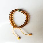 This handmade Citrine mala, crafted by skilled artisans in Nepal, features 20 beads and a marker bead, supporting mindful connection during spiritual practices and journeys.