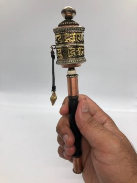 This handmade copper prayer wheel from Nepal is a sacred tool for meditation, featuring compassionate mantras and a wooden handle for a comfortable grip, deepening your spiritual practice.