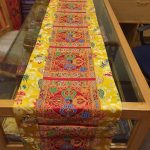 This handmade Tibetan table runner, crafted from silk brocade in Nepal, features a central double dorje, embodying the essence of wisdom and compassion for your meditation space.