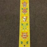 This handmade yellow silk brocade wall hanging showcases the Eight Jewels of Tibetan Buddhism, symbolizing prosperity and spiritual awakening, crafted by skilled artisans in Nepal.