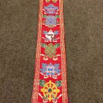 This handmade silk brocade wall hanging from Nepal showcases "The Eight Jewels," sacred symbols of Tibetan Buddhism, inspiring blessings and spiritual prosperity in your space.