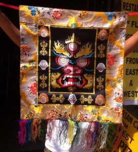 This handmade Tibetan silk brocade apron, crafted in Nepal, features Mahakala's powerful visage, symbolizing protection and transformation, serving as both a ceremonial garment and a spiritual wall hanging.