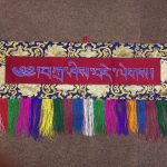 This handmade Tashi Delek wall hanging, crafted by skilled artisans in Nepal, features a lotus design that embodies auspiciousness and blessings, enriching your space with spiritual significance.