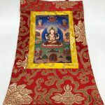 This handmade Chenrezig thangka wall hanging from Nepal embodies compassion and wisdom, beautifully encased in silk brocade, perfect for enriching your spiritual space.