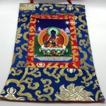 This handmade Medicine Buddha thangka from Nepal, adorned with silk brocade, invites healing and serves as a spiritual focal point for your sacred space.