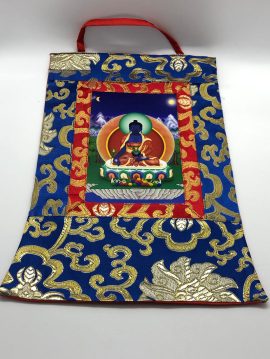This handmade Medicine Buddha thangka from Nepal, adorned with silk brocade, invites healing and serves as a spiritual focal point for your sacred space.