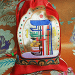 This handmade silk brocade mala pouch, adorned with a sacred Kalachakra design, is crafted by skilled artisans in Nepal, offering a protective space for your prayer beads.