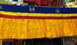 The Tibetan shambu, a handcrafted ruffled banner from Nepal, enhances sacred spaces with vibrant colors and eight auspicious symbols, inviting blessings and serenity into your home.