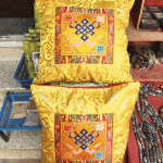 This handmade Tibetan silk brocade cushion cover features the Endless Knot, symbolizing the interconnectedness of life. Crafted by skilled artisans in Nepal, it enriches your space with sacred meaning.
